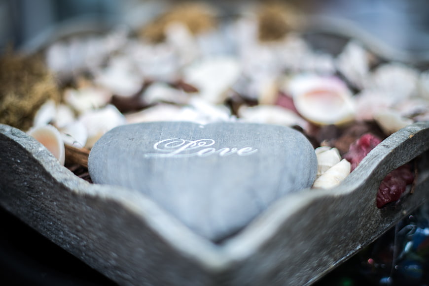 Heart-shaped stone engraved with love in wooden bowl