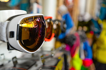 Close-up of white ski goggles with amber lenses on display rack