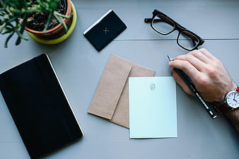 Flat lay of hand writing on desk with notebook and glasses