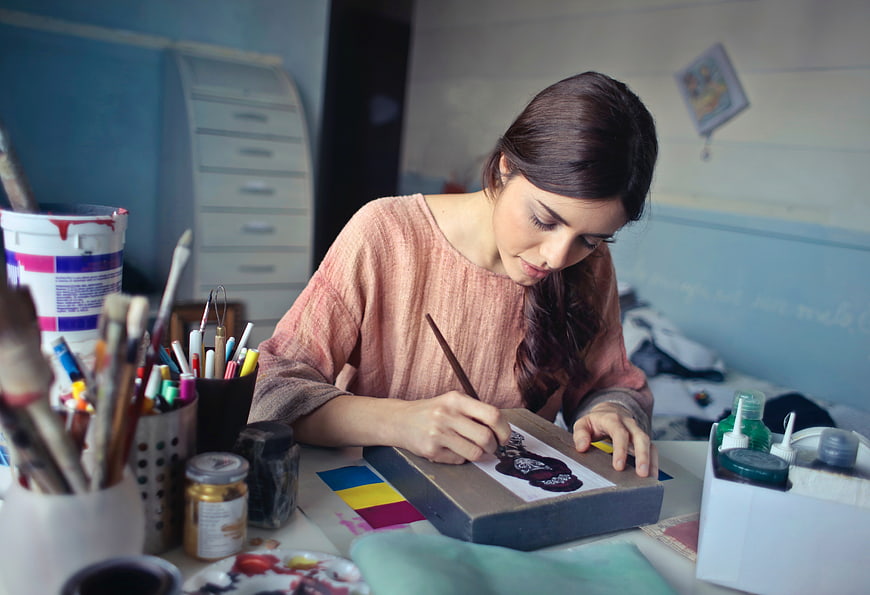 Young woman painting detailed artwork in creative studio