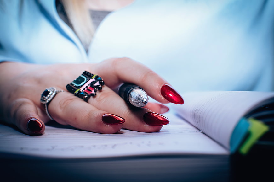 Woman's Hand with Red Nails Writing in Notebook