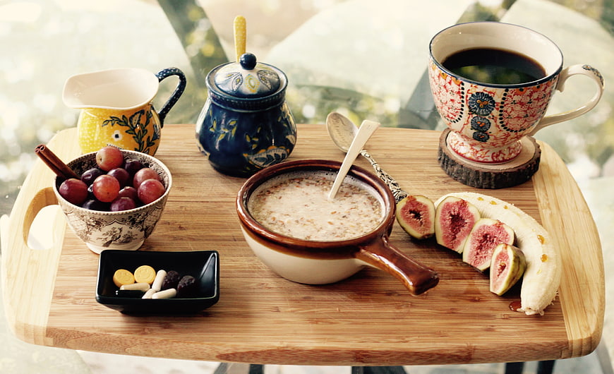 Healthy breakfast with oatmeal, fresh fruits, and coffee on a wooden tray