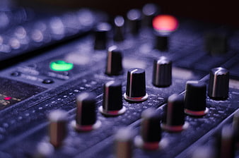 Close-up of audio mixer knobs with glowing green and red lights