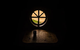 Dark moody interior with round window and wooden table