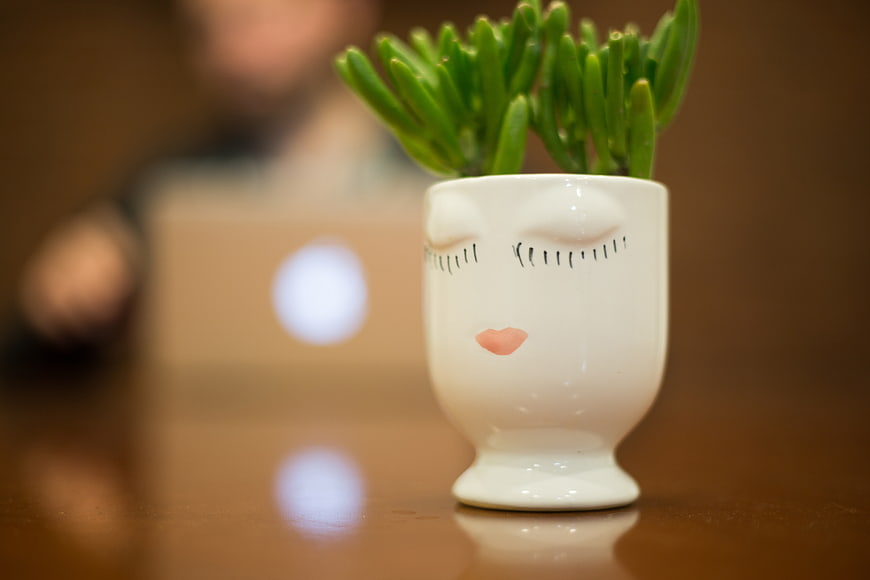 Cute ceramic face planter with succulent on office desk