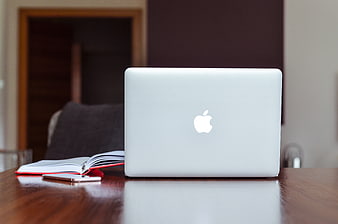 Closed MacBook on Wooden Desk with Notebook and Smartphone