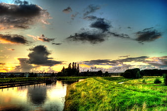 Dramatic HDR sunset over canal with green grassy banks
