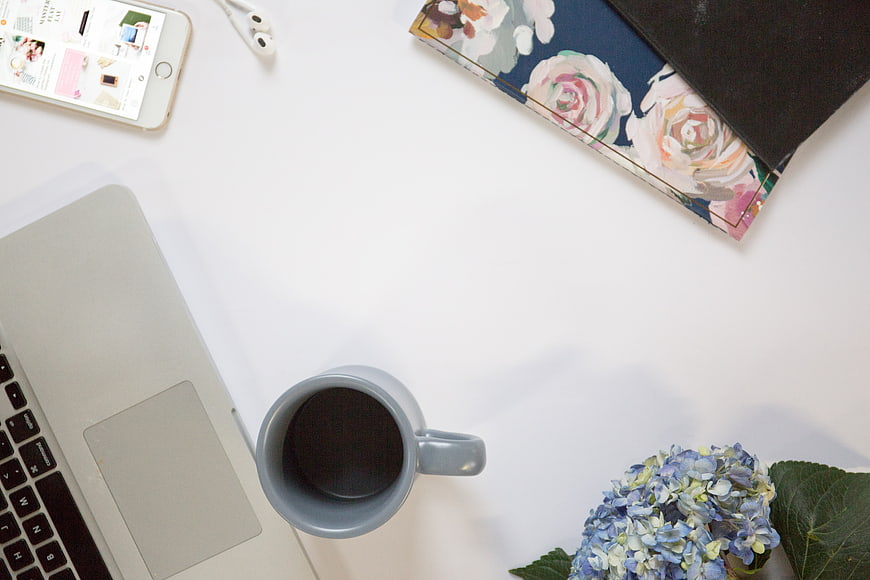 Minimalist workspace flat lay with laptop, coffee, and flowers