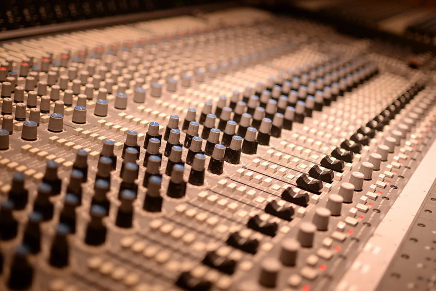 Close-up of professional audio mixing console with knobs and sliders