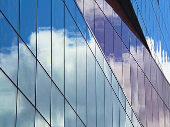 Modern Glass Skyscraper Reflecting Blue Sky and Clouds