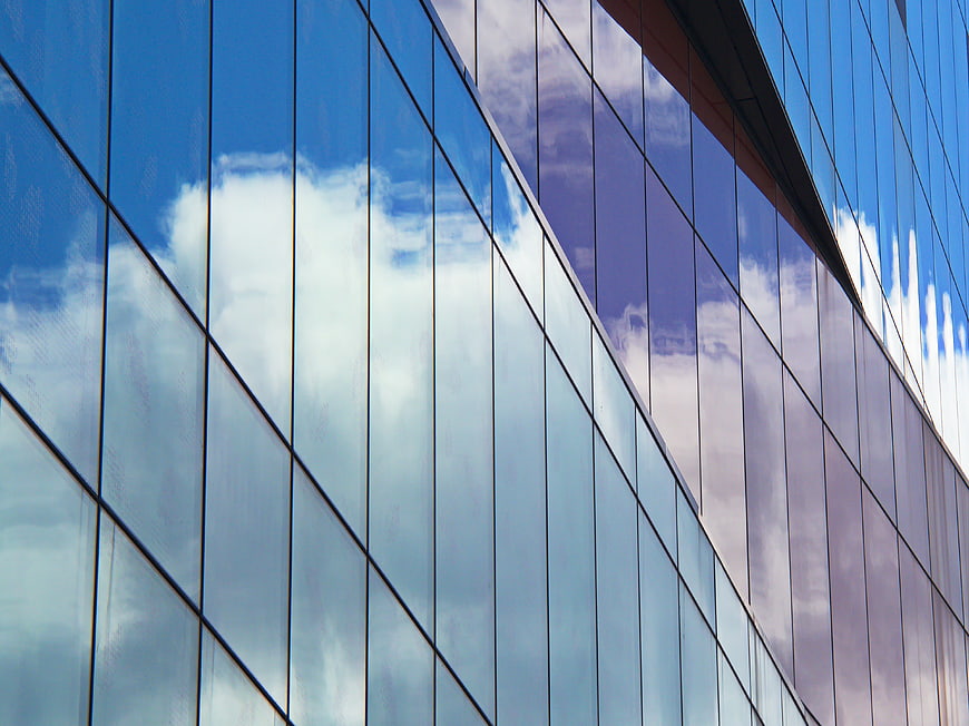Modern Glass Skyscraper Reflecting Blue Sky and Clouds