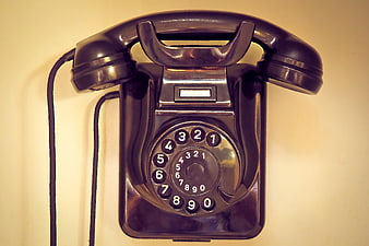Vintage black rotary telephone on a cream wall
