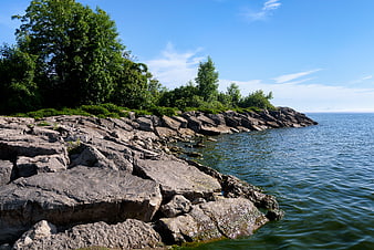 Rocky shoreline with green trees and blue water landscape
