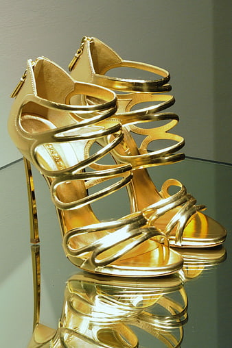 Gold strappy high heels on reflective surface