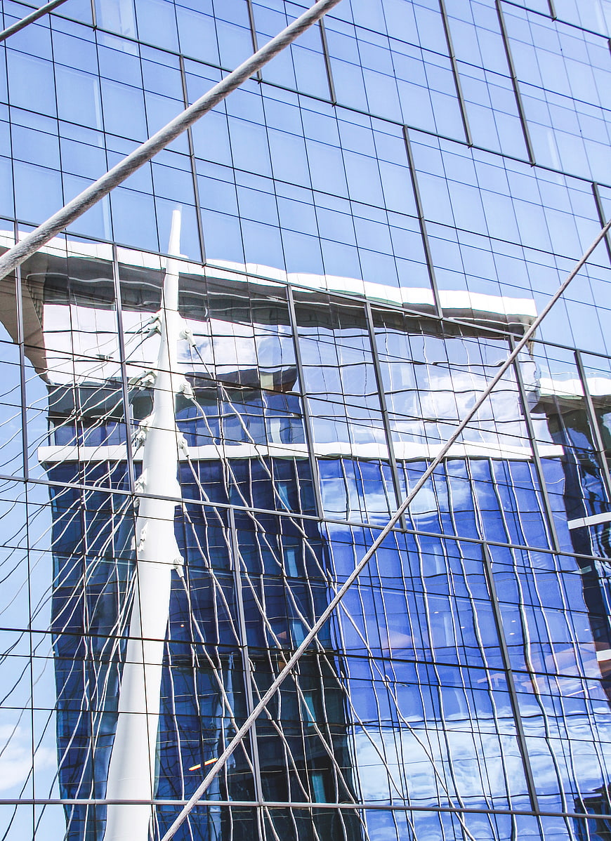 Modern glass building facade with sky reflection