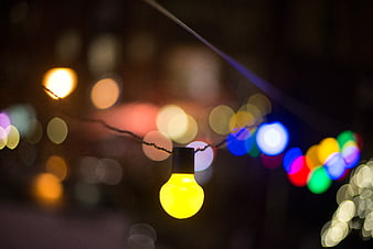 Close-up of glowing yellow Christmas light bulb with bokeh background