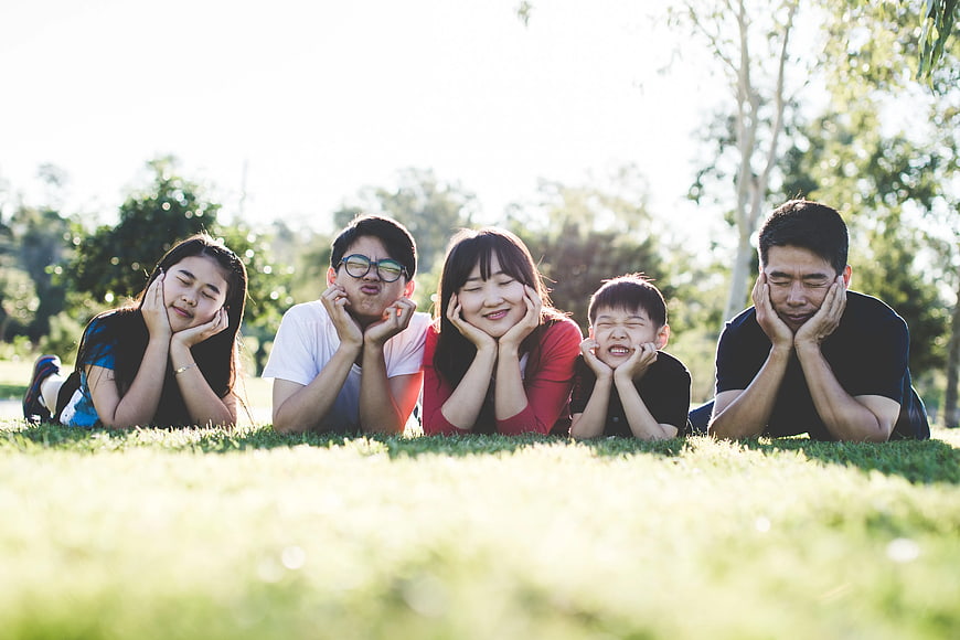 Happy Asian Family Lying on Grass in Park