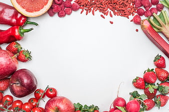 Flat lay of red fruits and vegetables on white background