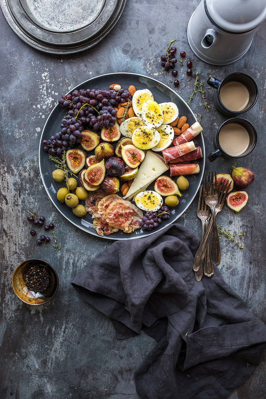 Overhead view of gourmet charcuterie board with figs, cheese, and coffee