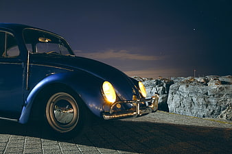 Vintage Blue Volkswagen Beetle at Night with Headlights On