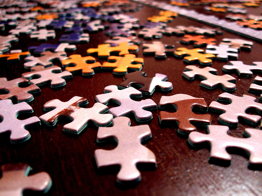 Scattered Jigsaw Puzzle Pieces on Dark Wood Surface