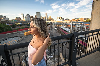 Stylish Blonde Woman Portrait on Urban Bridge with City Skyline