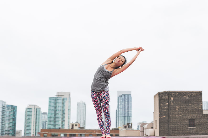 Asian woman stretching on urban rooftop with city skyline