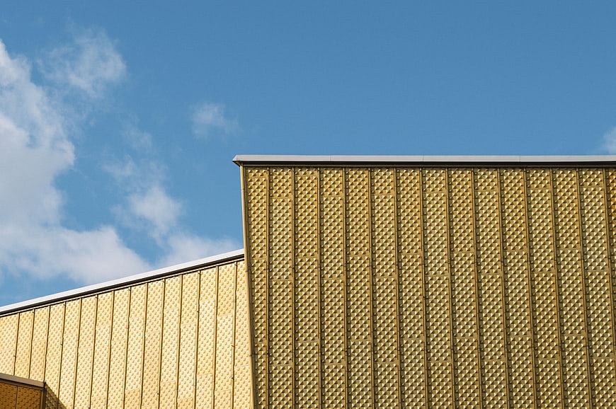 Modern golden textured building facade against blue sky