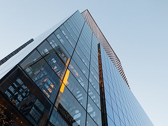 Low angle view of modern glass skyscraper with sunset reflection