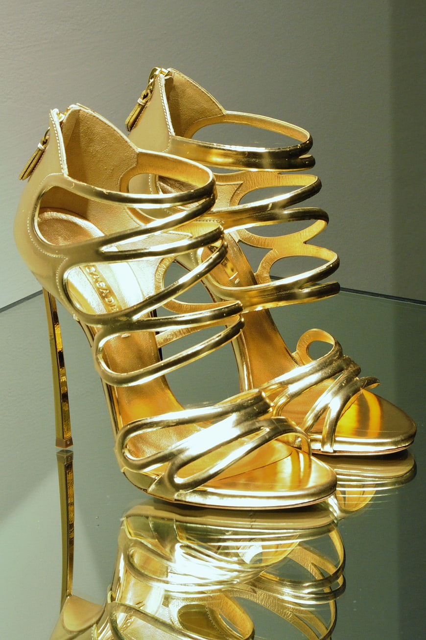 Elegant Gold Strappy High Heels on Reflective Surface