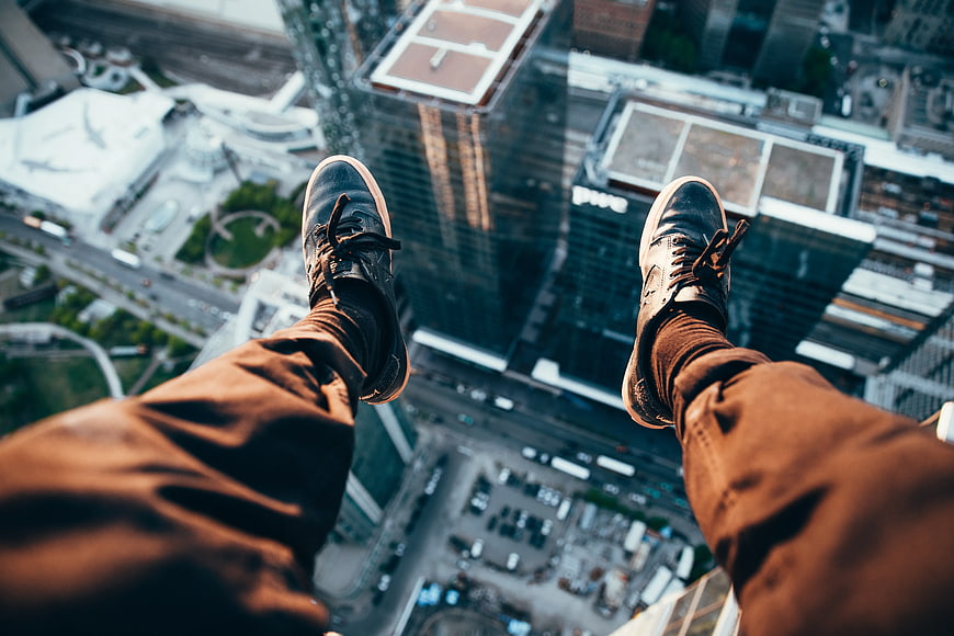 First-person view of sneakers dangling over city skyscrapers