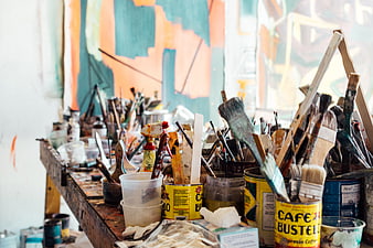 Cluttered artist workbench with paint brushes and supplies