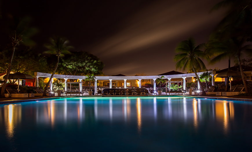 Luxury resort swimming pool at night with palm trees