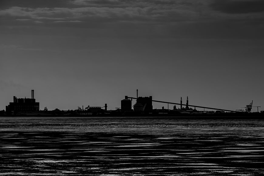 Silhouette of industrial harbor skyline over dark water