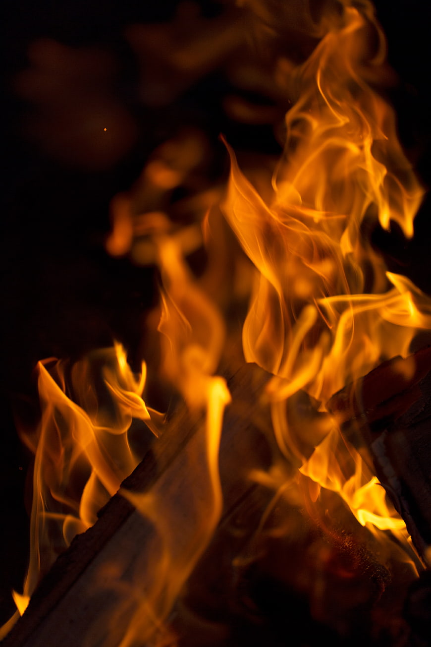Close-up of vibrant orange and yellow flames burning wood at night