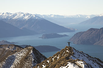 Hiker standing on snowy mountain peak overlooking lake