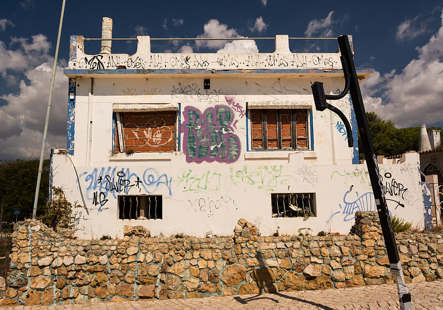 Abandoned white house with colorful graffiti and stone wall