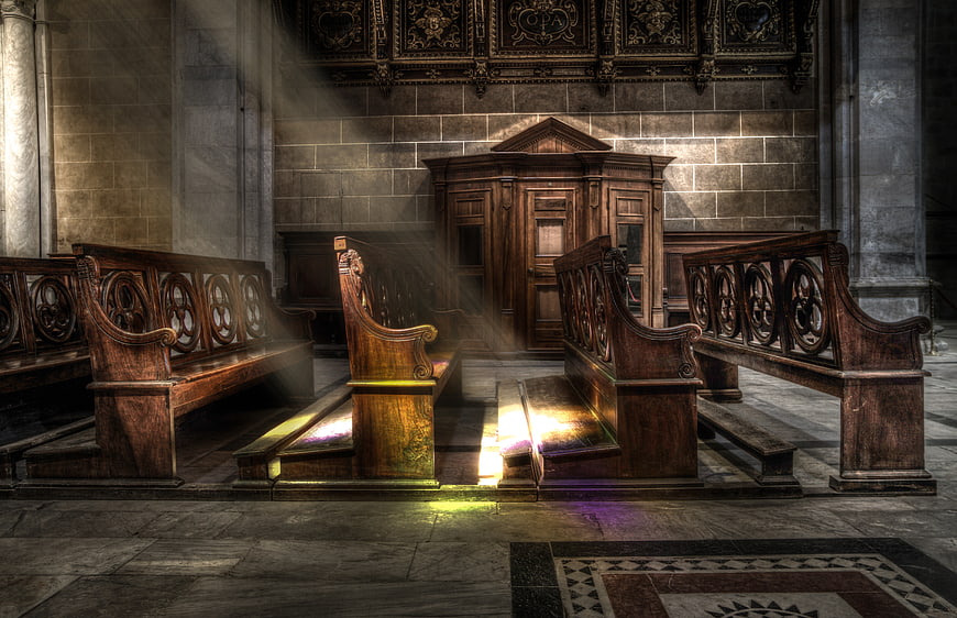 Sunbeams illuminating wooden pews in an empty cathedral interior
