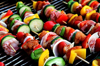 Colorful raw chicken and vegetable skewers on grill