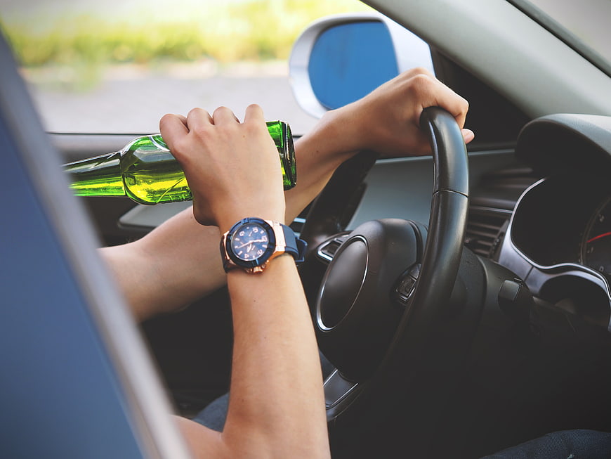 Person drinking beer while driving a car