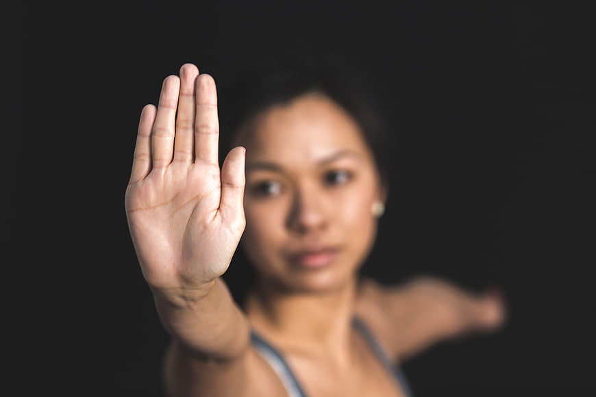 Woman holding hand up in stop gesture against black background