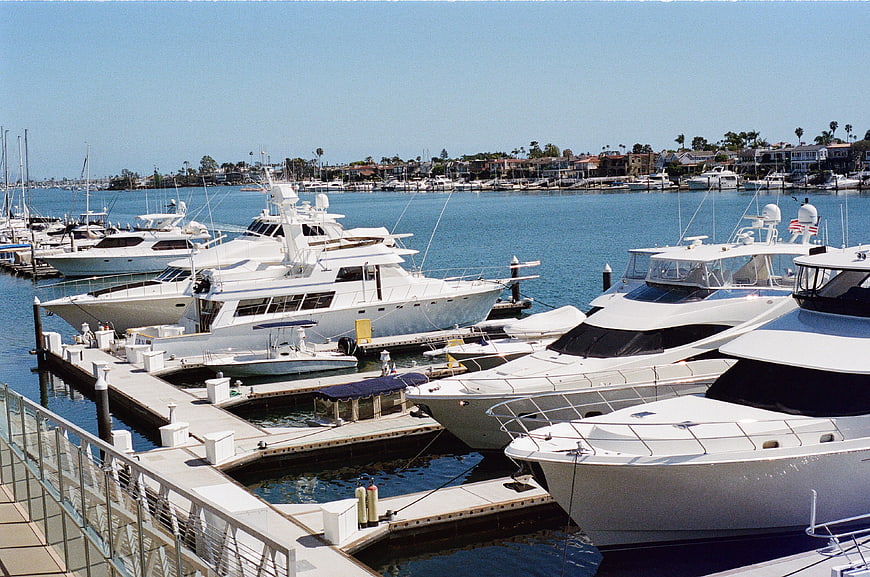 Luxury Yachts Docked at Sunny Marina with Coastal Houses