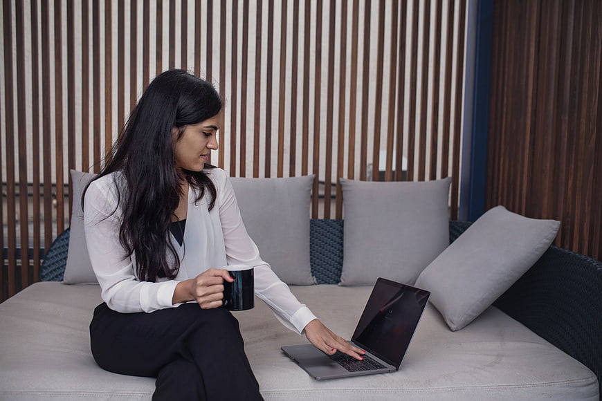 Professional woman working on laptop with coffee on patio