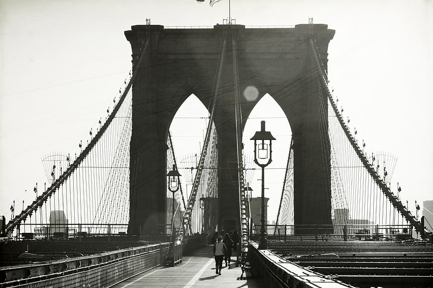 Black and white photo of Brooklyn Bridge arches and pedestrians