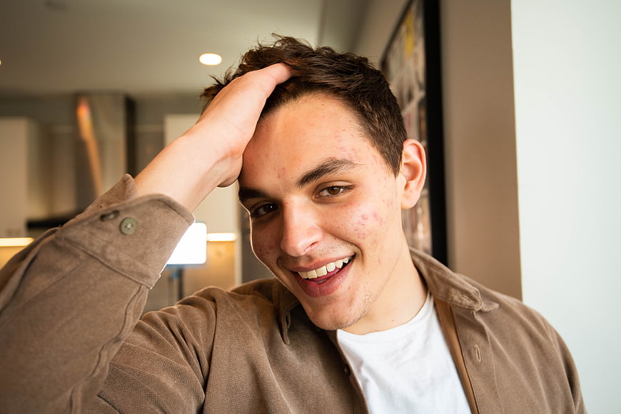 Smiling young man with hand on head in casual indoor setting