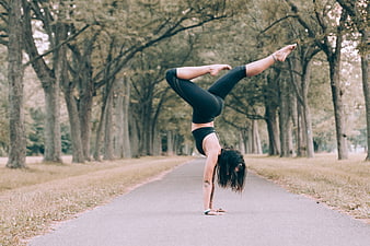 Woman performing advanced yoga handstand in park