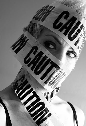 Woman's face wrapped in caution tape black and white