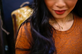 Close-up of woman wearing orange sweater and gold necklace