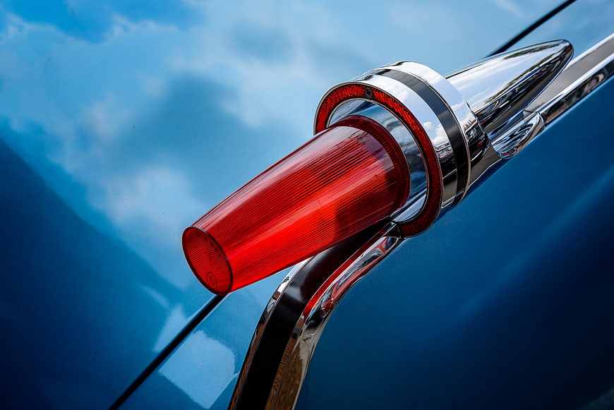 Close-up of vintage blue car chrome tail fin and red taillight