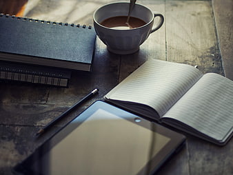Workspace with coffee, notebook, and tablet on wooden table